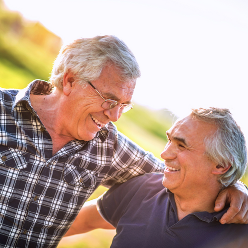 Two older men laughing and smiling outside