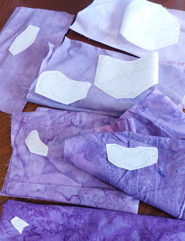 placing fusible webbing cutouts on appropriate purple fabrics to make a hollyhock applique block