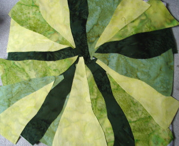 pieces of green fabric adhered to a sandwich of backing, batting, and fusible