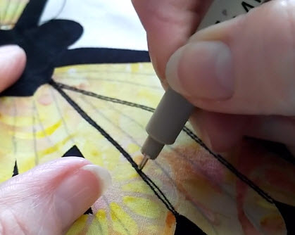 using a fabric pen to color in the outlines on a butterfly wing