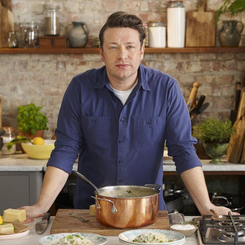 Chef Jamie Oliver stood in kitchen with ingredients on counter