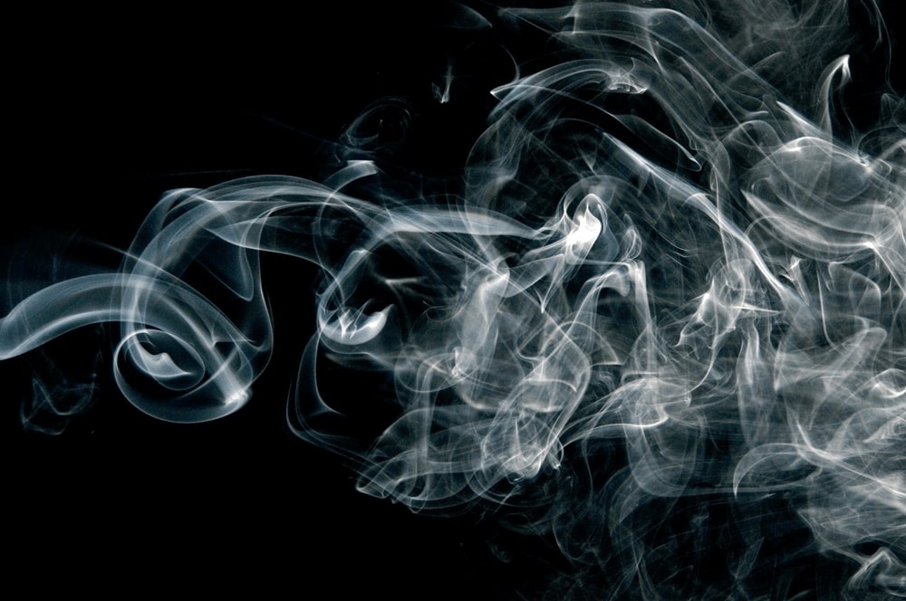 Smoke on a black background questioning the effectiveness of an air purifier.