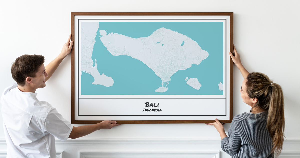 Cute happy couple hanging a poster map art of Bali, Indonesia.