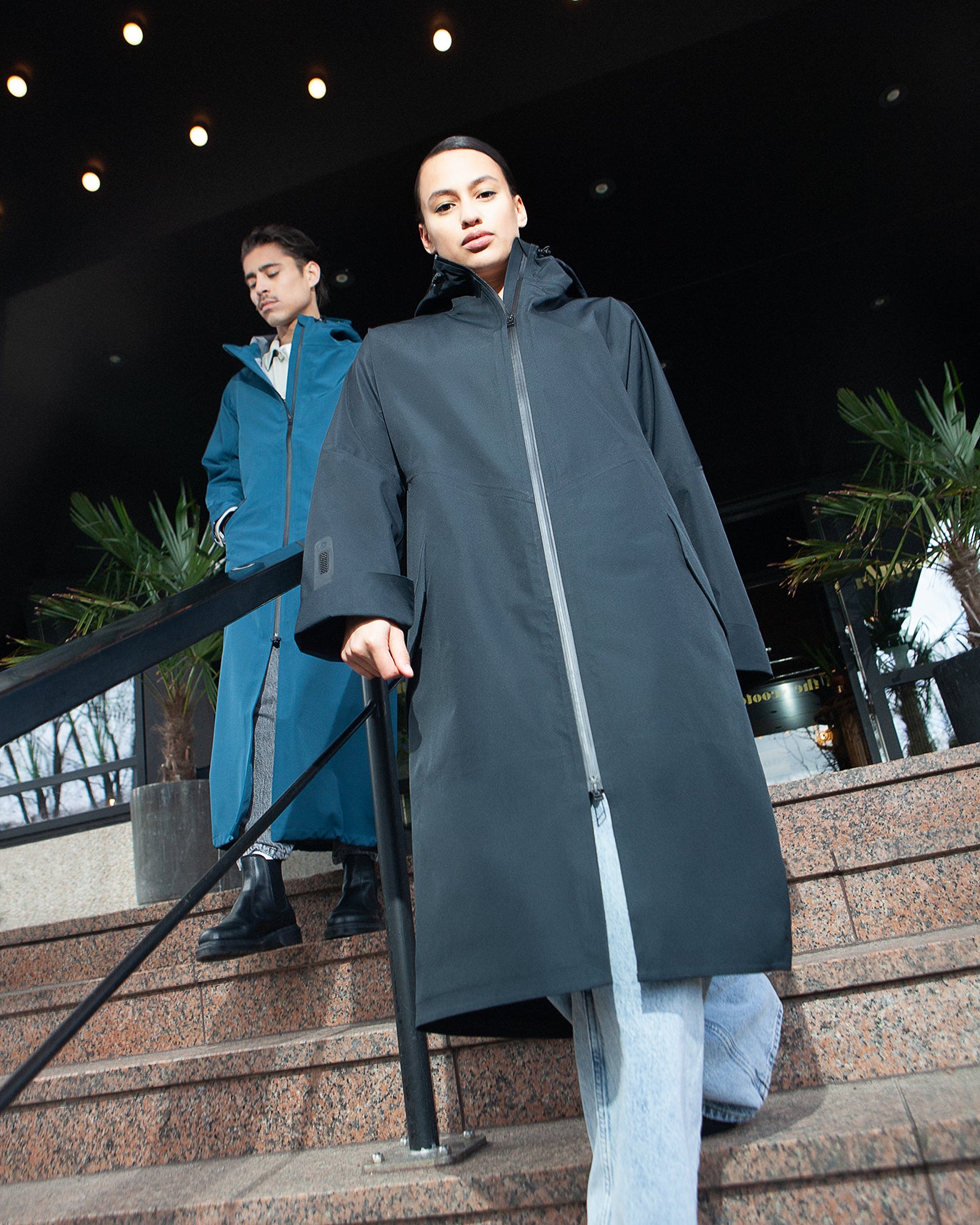 rent a raincoat at hotel v in Amsterdam, two models wearing the rainwear walking out of the hotel