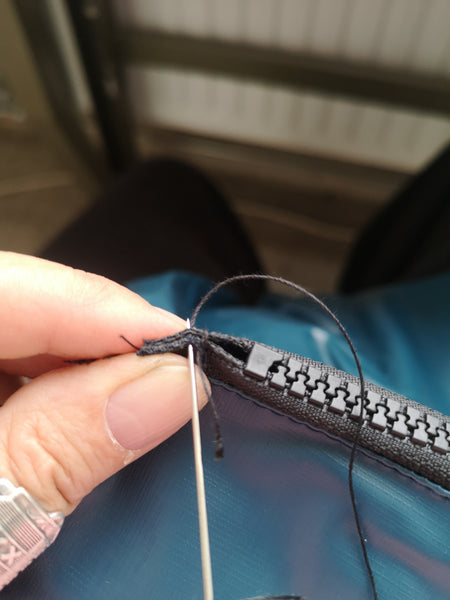 mending a coat with needle and thread for sustainability and long life