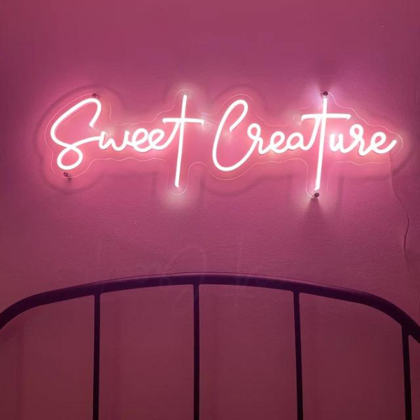 Sweet Creature neon light in the colour pink. The neon light is installed above the bed head in bedroom. Neon light produced by Neon Partys.