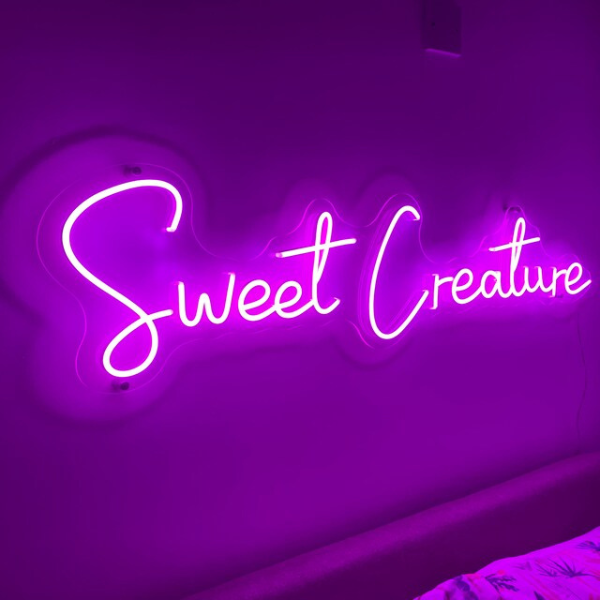 Sweet Creature neon sign in purple installed into the wall. Photo taken by customer. Sign produced by Neon Partys.