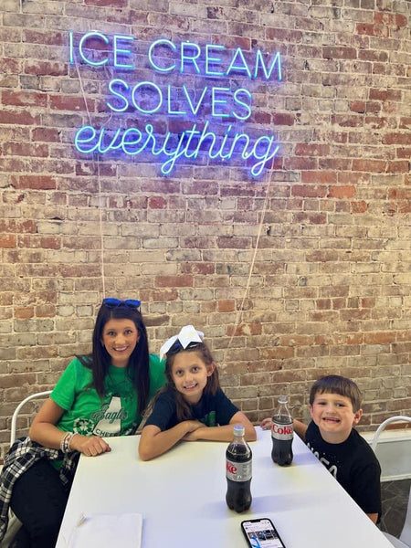 A happy family enjoying their ice-cream and posing infront of the neon light