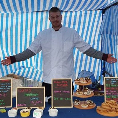 Michael wearing a chef's jacket presents a selection of delicious cakes at a market