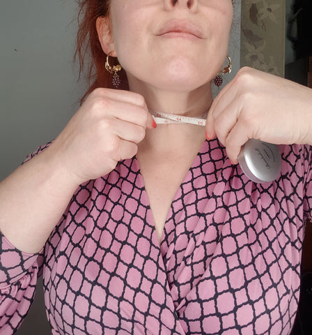 A woman measuring her neck with a tape measure