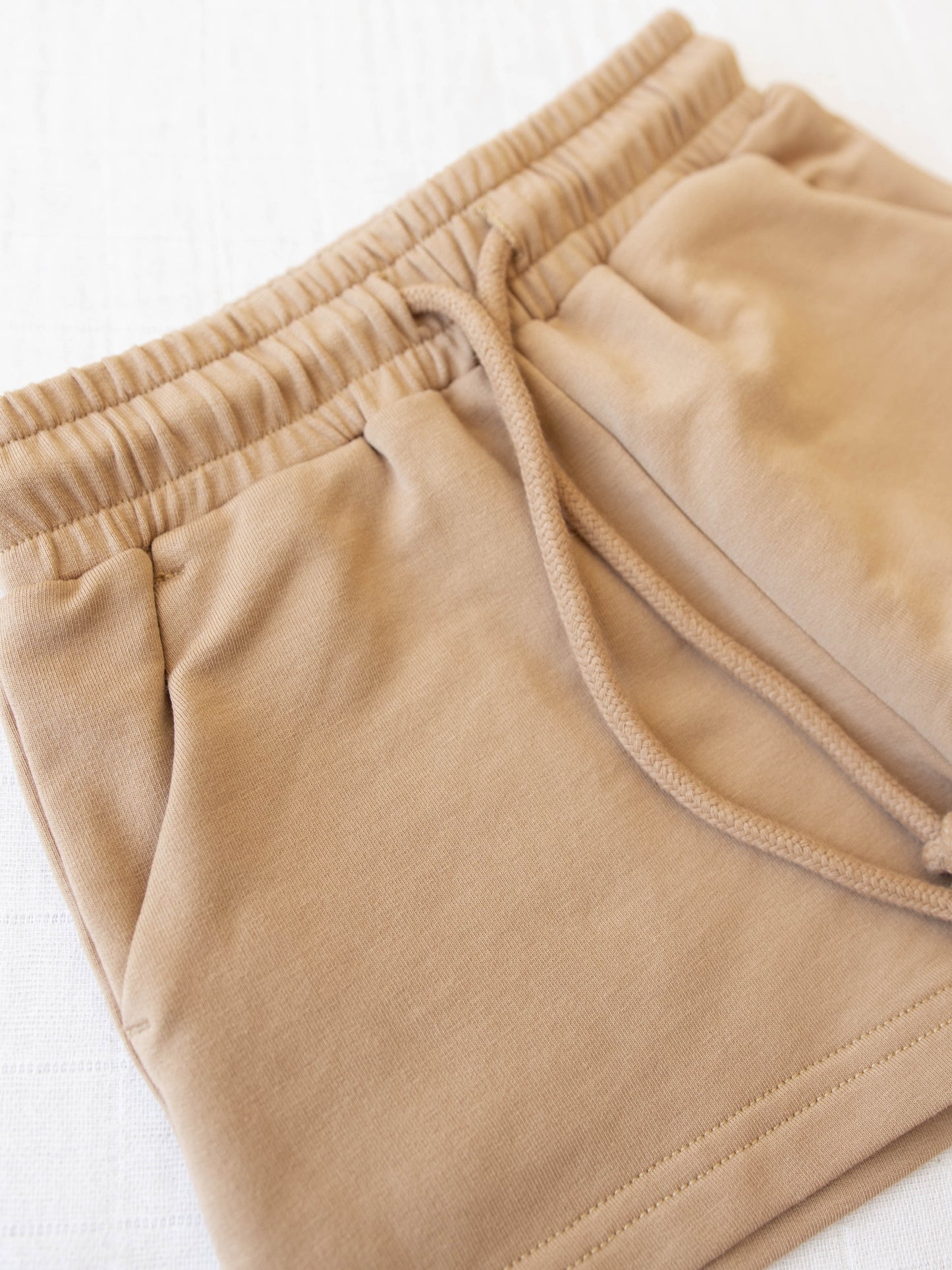 Closeup of the shorts with an elastic waistband, pockets, and functional drawstring.