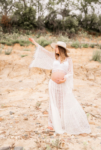 Maternity photoshoot of woman in white boho style dress in an outdoor scene