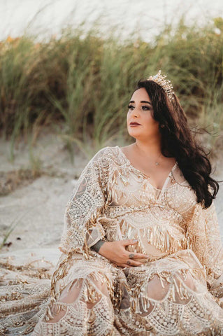 pregnant lady wearing a gold sequin glam maternity dress in beach photoshoot