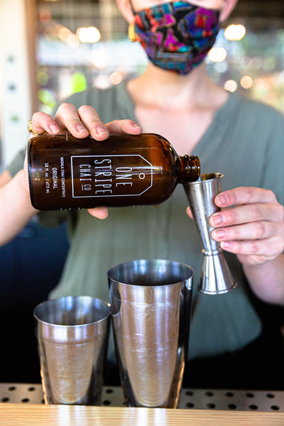 Bartender is pouring One Stripe Chai concentrate into a shaker to make Not Your Mom's Chai bourbon cocktail