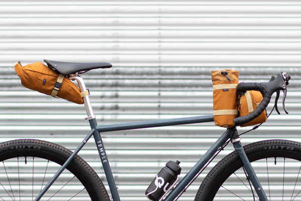 Temple Cycles charcoal bike with orange handle bar and saddle bags