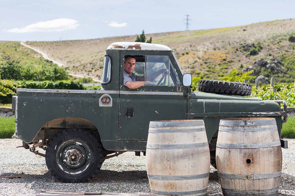 Green pick up with 2 barrels of Sporting Wine's wine in front with a mountain backdrop