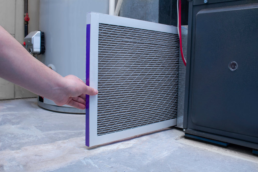 A person inserting the home furnace filter in HVAC system