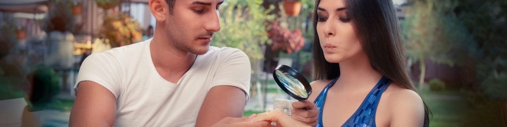 woman looking at engagement ring through magnifying glass