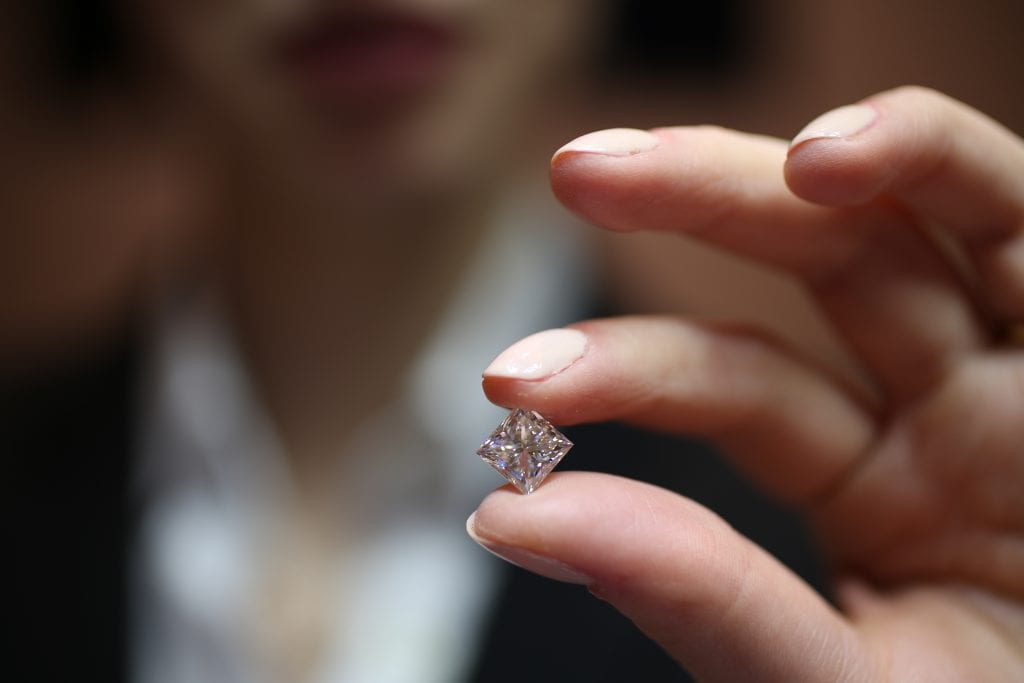 diamond consultant holding a 3 carat princess cut diamond