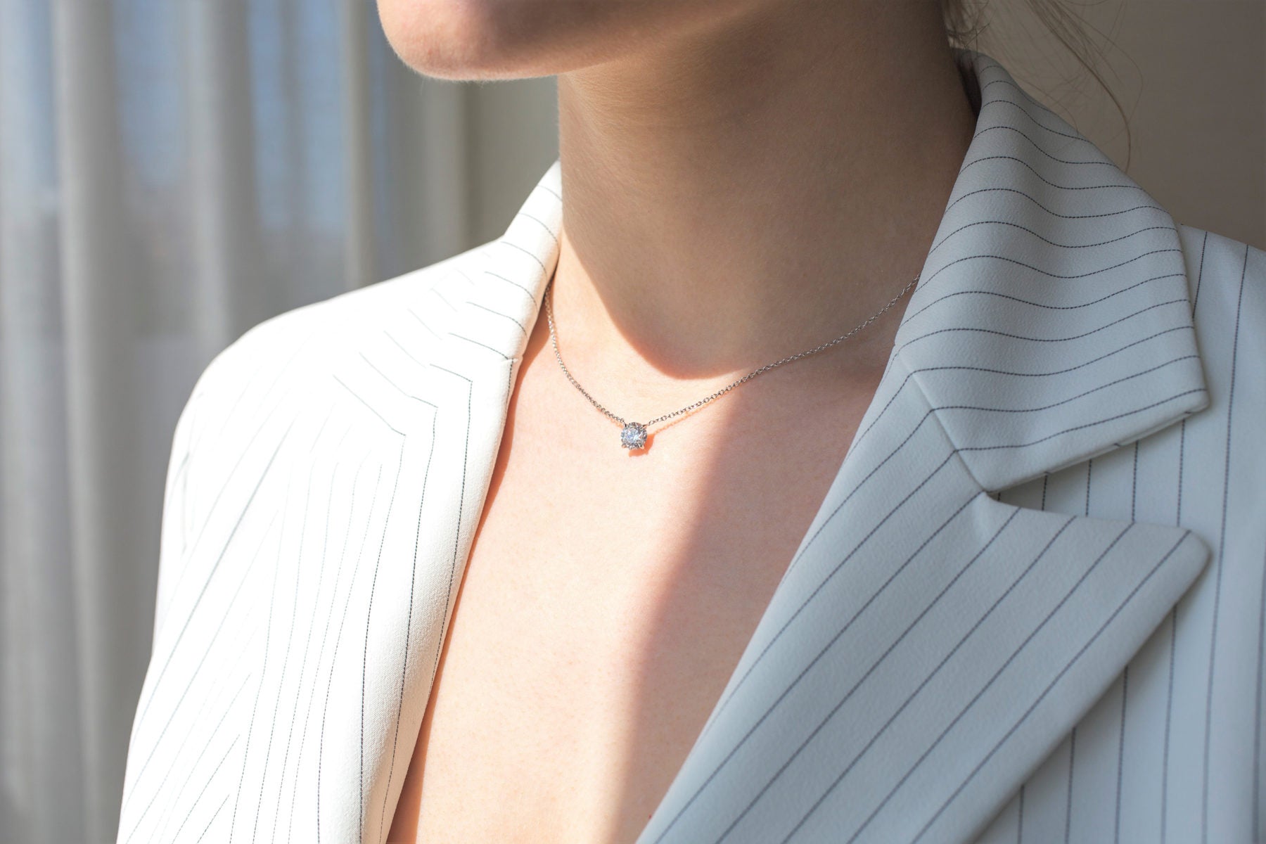 woman wearing solitaire diamond necklace