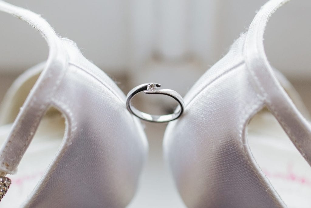 tension set diamond ring between wedding shoes