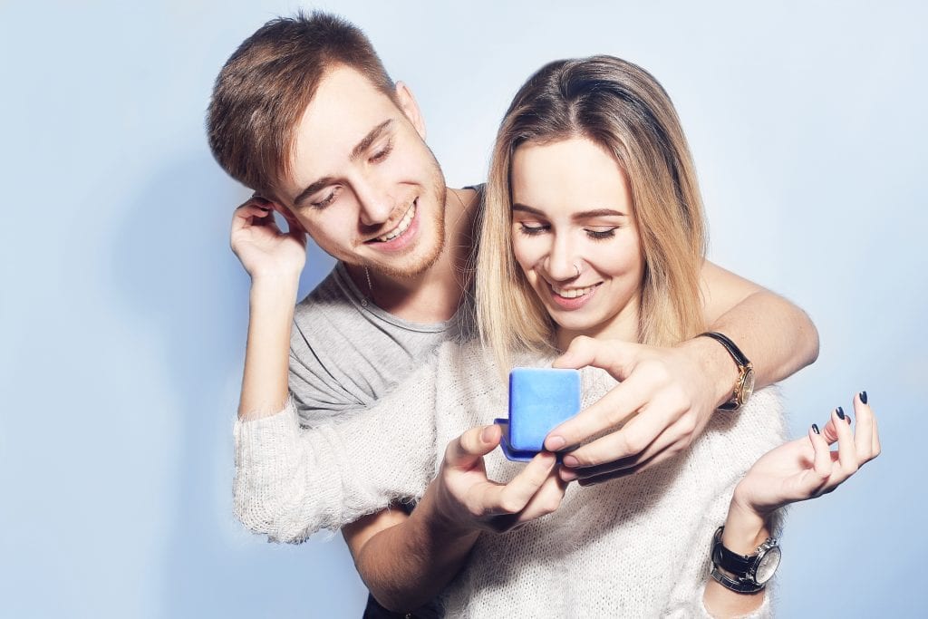 young man giving a ring in a box to his girlfriend