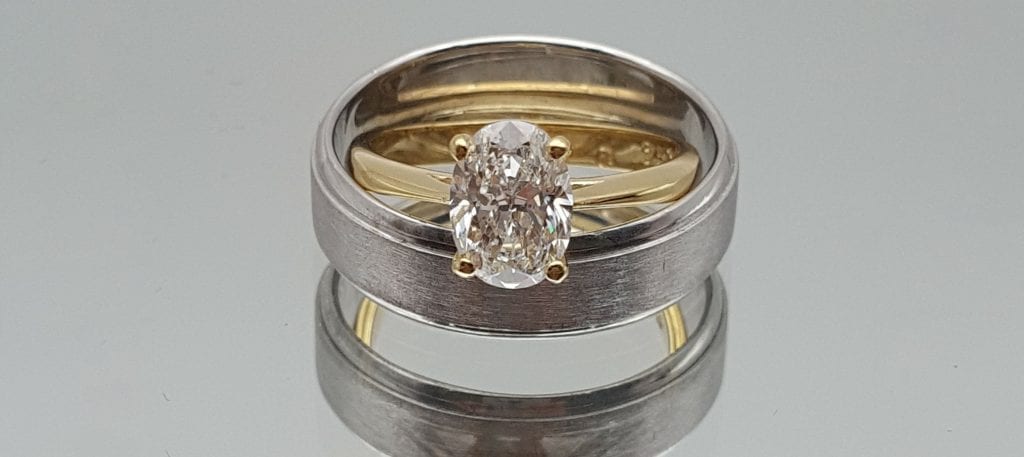 two wedding rings one with oval diamond