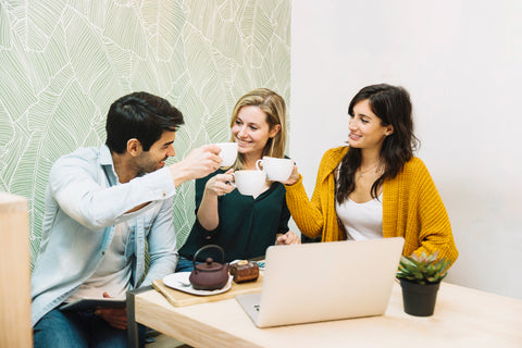 Three people raising their coffee cups together