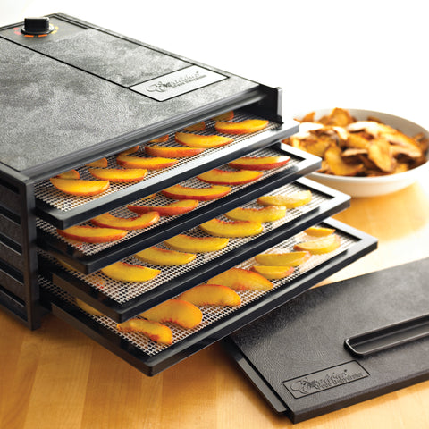 Sliced peaches on trays of a 4 tray Excalibur dehydrator.