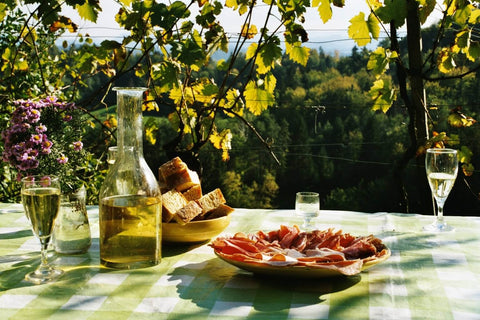 Picnic table set with wine glasses and food.