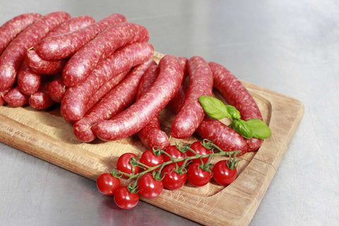 Sausages on a wooden board with tiny tomatoes.