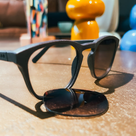 Close-up van een zonnebril montuur zonder glazen. De glazen liggen op de tafel voor het montuur.