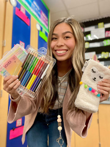 Jaelyn Lozano holding 30pk gel pens, colored pencils, and llama pencil case