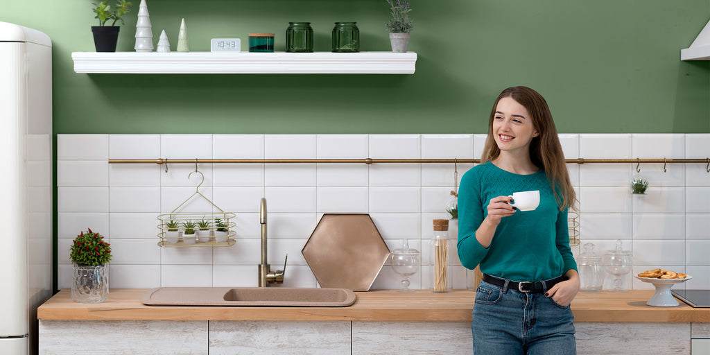an image showcasing that a women standing in the kitchen and holding a coffee cup
