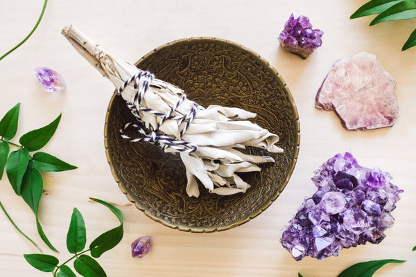 Amethyst crystal, rose quartz crystal and sage arranged with fresh green leaves