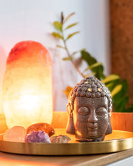Buddha head decor next to a glowing Himalayan salt lamp