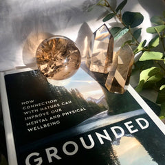 Smoky Quartz Crystal Sphere and Tower glow in the late sunshine on a hardback book
