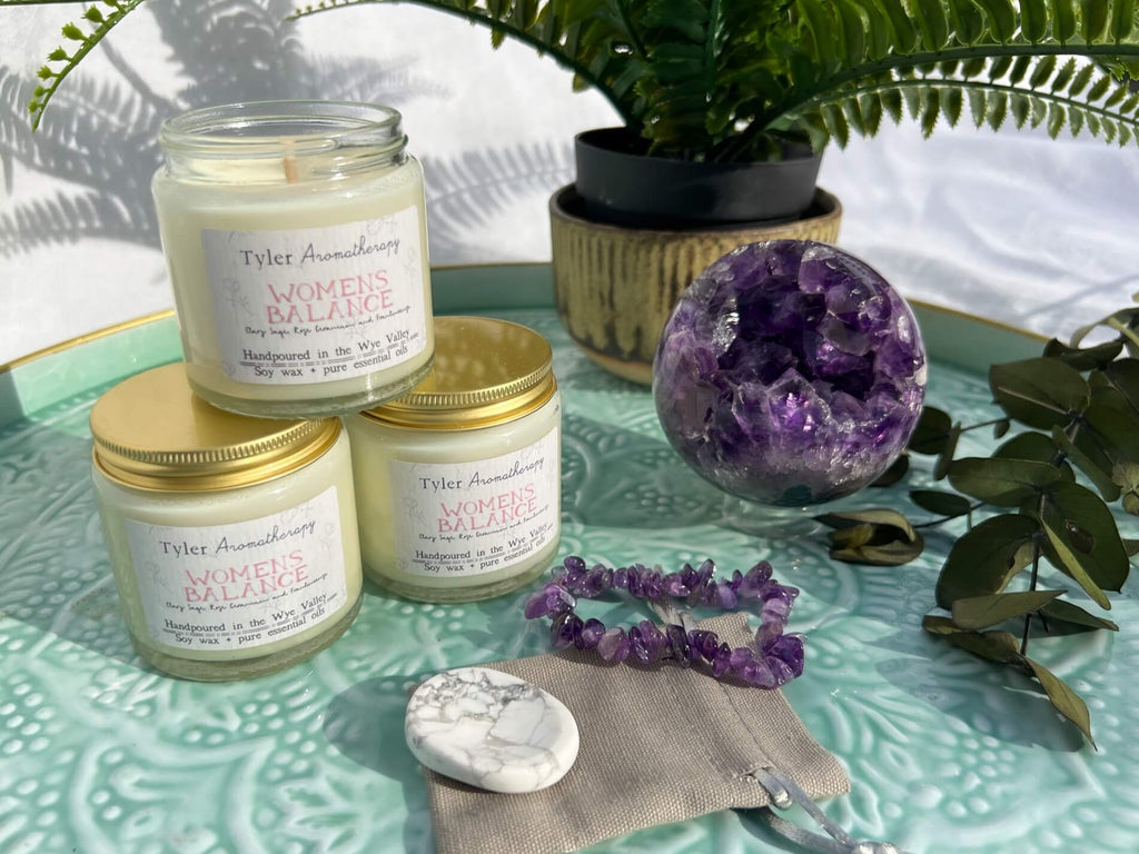 Women's mood balancing aromatherapy candle with a purple amethyst geode sphere, hoplite worry stone and amethyst chip bracelet on a turquoise enamel tray