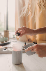 Essential oils being dripped into an aromatherapy diffusers by a woman