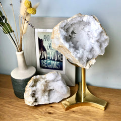 Large clear quartz geode crystal displayed on a brass stand on a bedside table