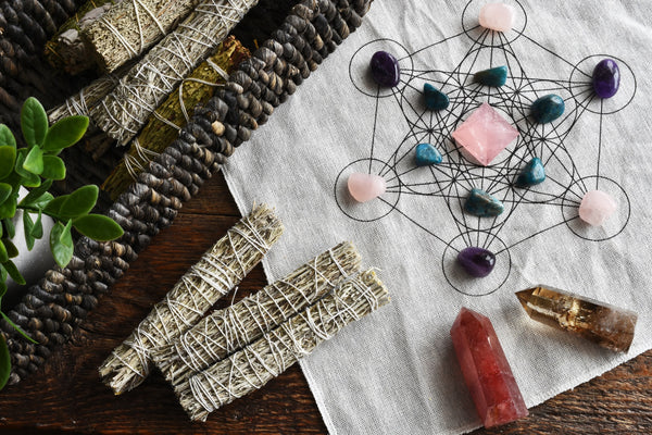 Crystal protection grid laid next to a small wooden box full of spiritual sage bundles