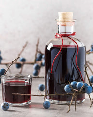 Bottle of sloe gin tied with red string and springs of sloe berries