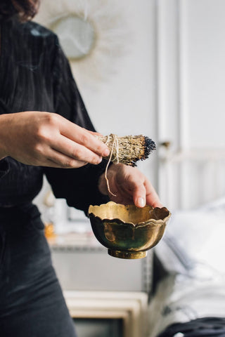 A woman smoke cleansing her home with a white sage stick