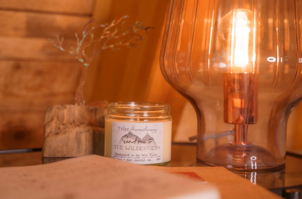 The Wilderness Aromatherapy candle burns in a cosy corner next to a lamp