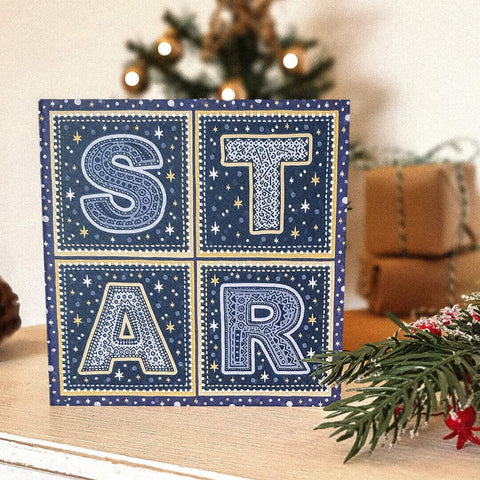A navy blue festive card with letterpress letters spelling STAR