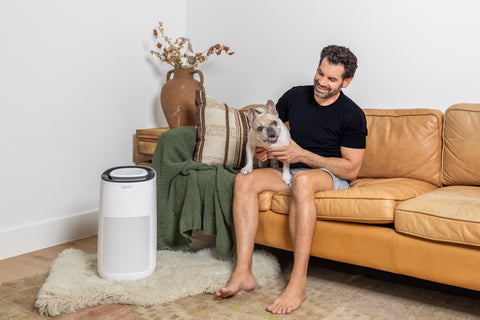 man sitting on couch holding dog