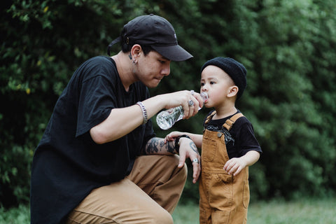 Dad giving his son bottled water to drink