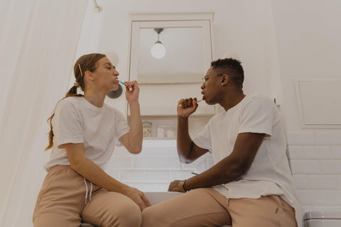 A man and woman brushing their teeth