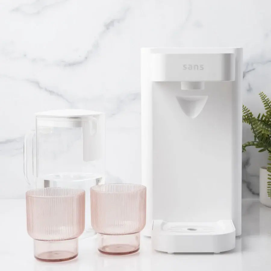White water filtration system with two pink glasses and a plant in the background.