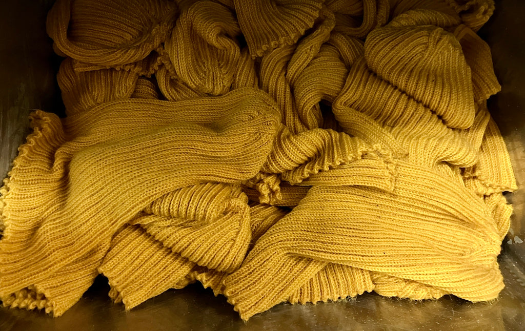 a pile of naturally dyed marigold wool beanies
